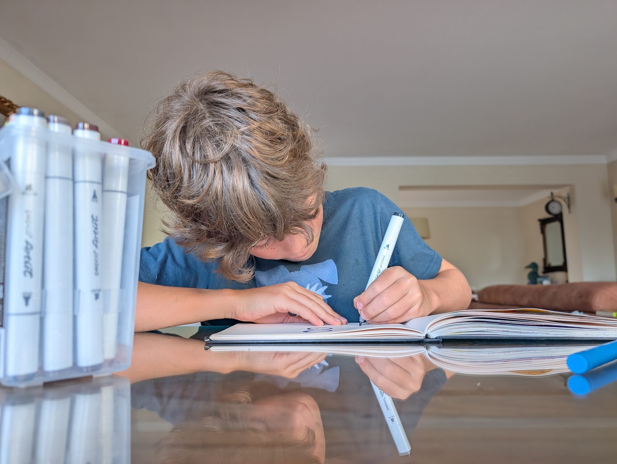 A child drawing in a notebook with marker pens